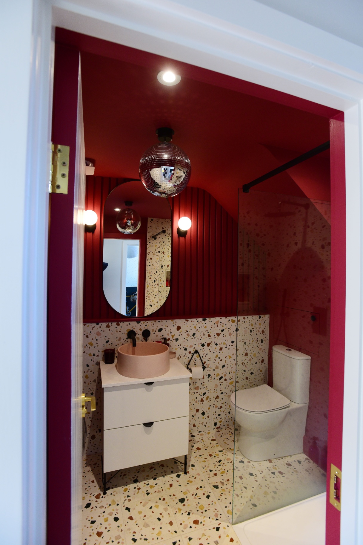 Bold red bathroom with a glitterball light fixture