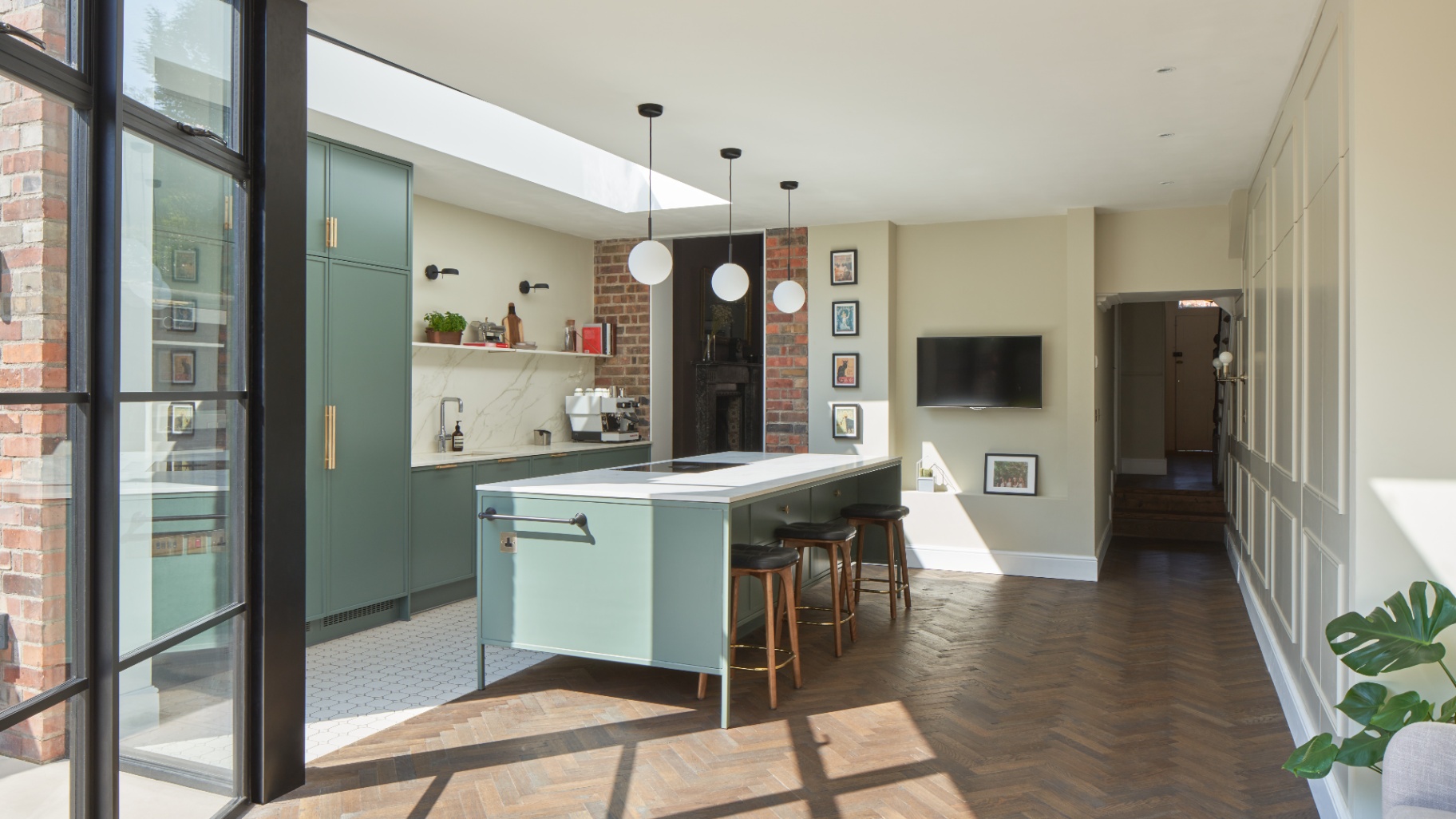 Wide shot of a sage green kitchen with a large island