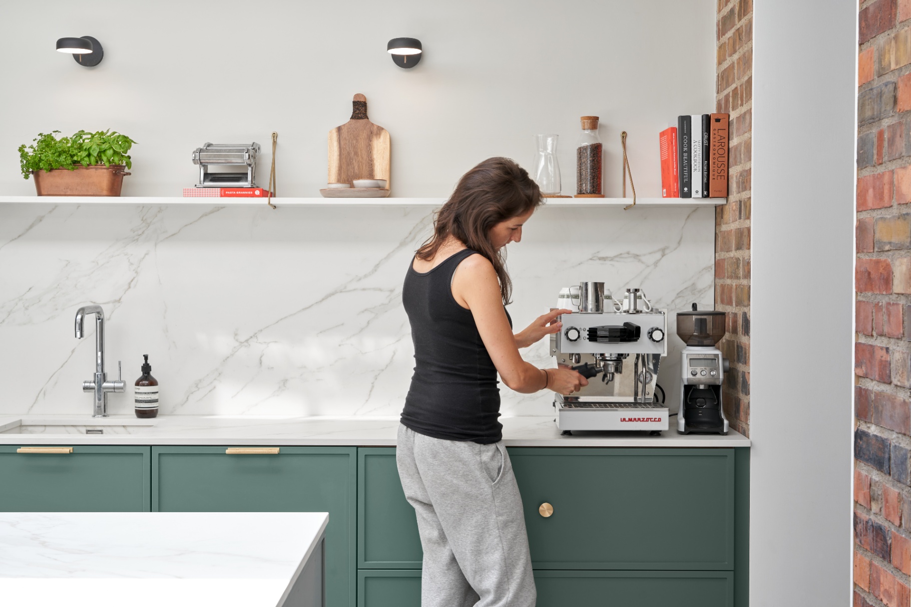 Kate using a professional espresso machine in the sage green kitchen