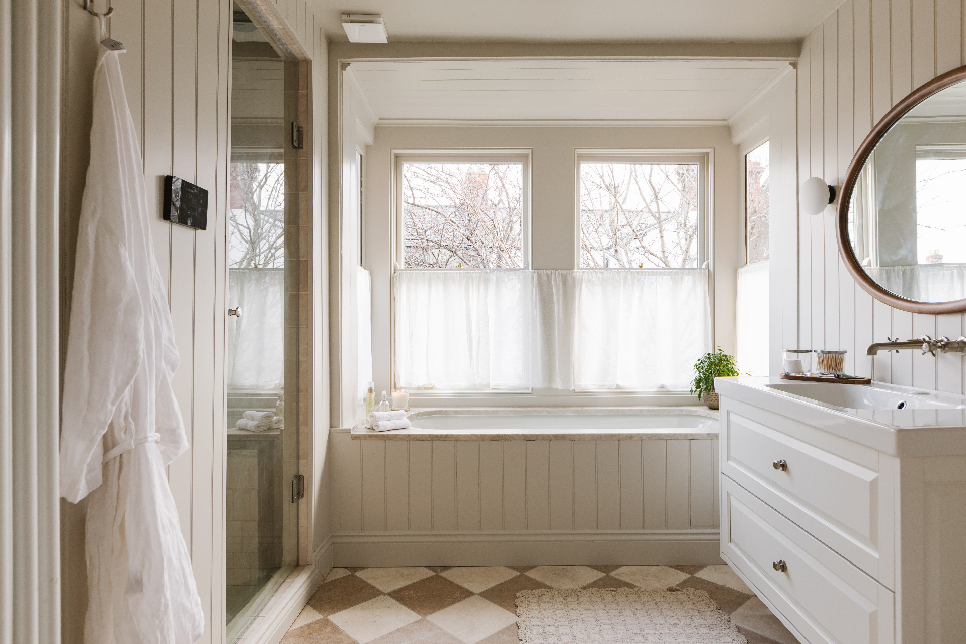 Panelled bathroom with checkerboard tile floor and freestanding bath